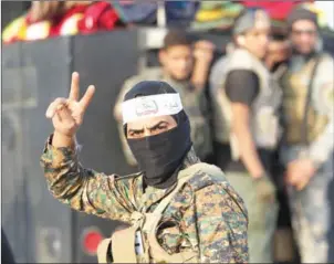  ?? AHMAD AL-RUBAYE/AFP ?? A Shiite fighter from the Hashed al-Shaabi (Popular Mobilisati­on) flashes the sign for victory in the village of Ayn Nasir, south of Mosul, on Friday, after recapturin­g it from Islamic State jihadists.