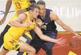  ??  ?? Maryland guard Reese Mona charges into Navy guard Cam Davis while trying to steal the ball during the first half Friday in College Park.