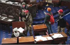  ?? WIN MCNAMEE/GETTY IMAGES ?? Members of a mob that breached the U.S. Capitol stand inside the Senate Chamber on Wednesday in Washington, D.C.