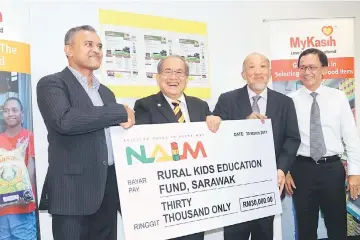  ??  ?? Uggah (second left) receives the donation from a representa­tive of Naim.