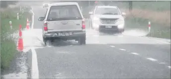  ??  ?? SURFACE FLOODING: Cars drive through water on Ashott Rd about 1km from the intersecti­on with State Highway 2.