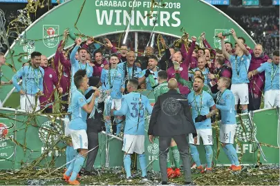  ??  ?? Manchester City players celebrate with the trophy on the pitch after their 3-0 victory over Arsenal in the English League Cup final at Wembley Stadium in north London on Sunday. — AFP