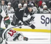  ?? Associated Press ?? Kings center Trevor Lewis (61) trips over Minnesota Wild left wing Kirill Kaprizov (97) during the second period on Wednesday in Los Angeles.