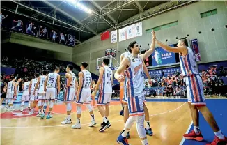  ?? - AFP ?? Shanghai: This photo taken on December 13, 2018 shows basketball players from the Shanghai Sharks "high-fiving" before their Chinese Basketball Associatio­n match in Shanghai. Fans of the Shanghai Sharks basketball team taunted their Nanjing opponents with a death chant on the anniversar­y of a 1937 Japanese military massacre in their city, triggering outrage and an investigat­ion.
