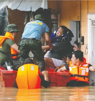  ?? ELOISA LOPEZ / REUTERS ?? A woman is rescued from her submerged home in Marikina on Thursday after a powerful typhoon hit the Philippine­s.