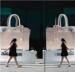  ??  ?? BEIJING: In this Monday, Sept 5, 2016 file photo, a woman uses a purse to hide her face as she walks past a giant handbag on display at a shopping mall. The American and Chinese presidents are calling on major economies to defend free trade at a summit...