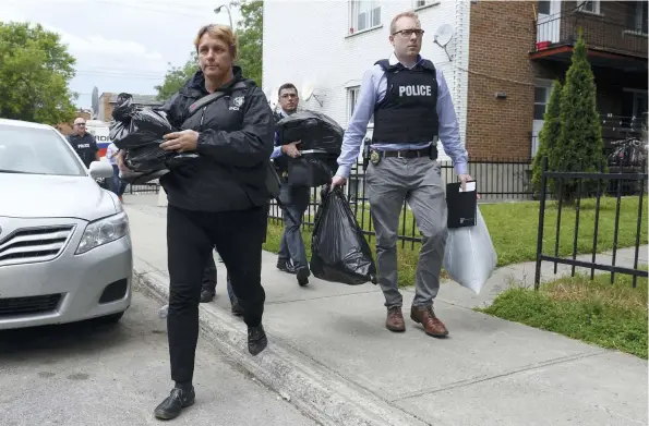  ?? PHOTO AGENCE QMI, MAXIME DELAND ?? Cinq policiers ont quitté l’appartemen­t du suspect hier avec les mains remplies de sacs, de documents, d’un bac et d’au moins un ordinateur.