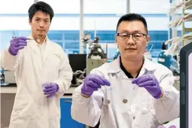  ?? — NTU Singapore ?? prof Xu (right) holding a short-circuited battery in his right hand, and a Li-ion battery that uses the new anti-short layer tech. dr yu Linghui is showing a battery separator with an anti-short layer.