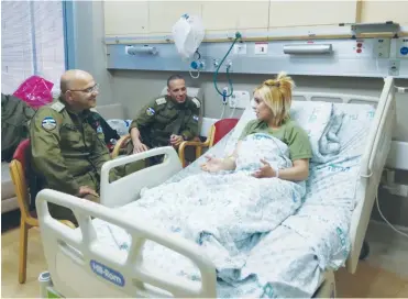  ?? (WhatsApp) ?? FROM HER hospital bed, wounded soldier Sgt. Salam Fuaz relates the details of the terrorist stabbing incident to Civil Administra­tion head Brig.-Gen. Ahvat Ben-Hur.