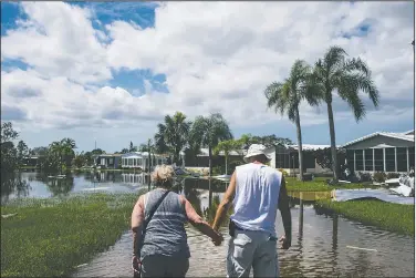  ?? AP/Naples Daily News/NICOLE RAUCHEISEN ?? Linda and Dave Stroshein hold hands Wednesday as they walk through a flooded Citrus Park to see their house for the first time since Hurricane Irma in Bonita Springs, Fla.