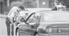  ??  ?? RCMP pull over a driver during a distracted-driving crackdown in March. The province has announced a big jump in penalties for drivers caught talking on cellphones or texting while driving.