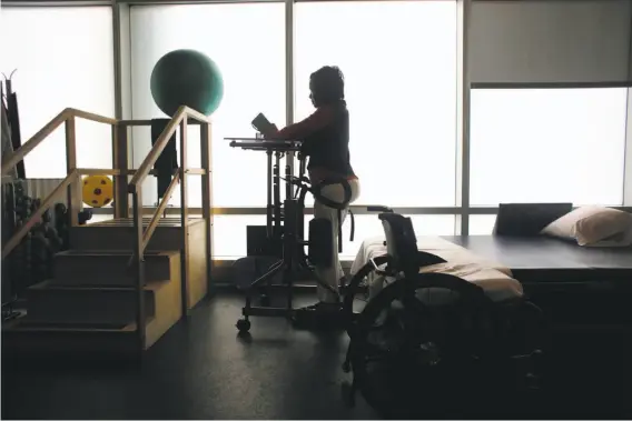  ??  ?? Below: Zhou is upright in a hydraulic standing frame during physical therapy in the Wellness Center at Laguna Honda.