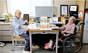  ??  ?? Masao (left) and Miyako look at albums in their room at a nursing house in Takamatsu, Kagawa prefecture. — Reuters photo