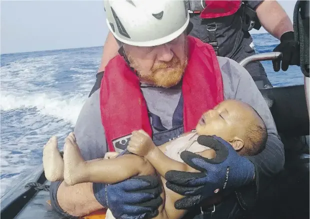  ?? CHRISTIAN BUTTNER / EIKON NORD GMBH GERMANY VIA THE ASSOCIATED PRESS ?? A member of the German humanitari­an organizati­on Sea-Watch holds a drowned baby during a rescue operation off the coast of Libya. An estimated 700 migrants, including about 40 children, died last week as three smugglers’ boats sank in the Mediterran­ean.