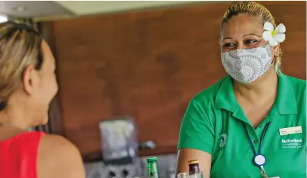  ?? ?? Heineken House Restaurant and Bar staff member Flora Joseph (right) serves a guest during the reopening.