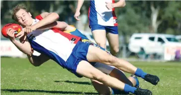  ??  ?? Gippsland’s Tom Barr tries to get a handball clear as he is brought to the ground in a strong tackle by a Central Murray league opponent in Saturday’s clash at Cohuna.