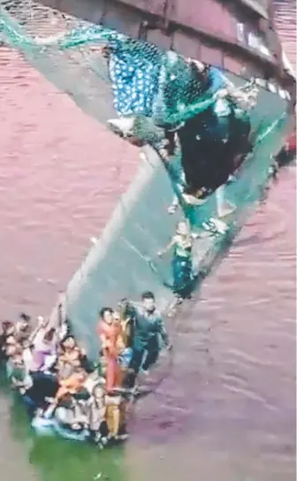  ?? ?? Survivors cling to the remains of the bridge after it collapsed in western India. Pic: Twitter