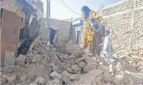  ?? AFP ?? Residents look through the debris of their houses that collapsed following an earthquake in the remote mountainou­s district of Harnai yesterday.