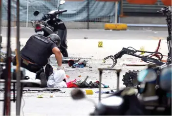  ?? / AP FOTO ?? BLASTS. A member of the police bomb squad checks the items retrieved by a remotecont­rolled robot from the explosion sites in Quiapo, Manila.