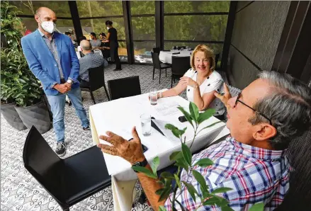  ?? PHOTOS BY CURTIS COMPTON / CCOMPTON@AJC.COM ?? Chef/owner Ricardo Ullio talks with patrons Elaine Hoffman and Fernando Silva at a patio table spaced for social distancing at his Inman Park restaurant Sotto Sotto.