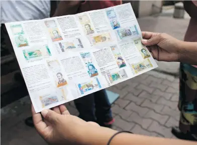  ?? ARIANA CUBILLOS / THE ASSOCIATED PRESS ?? A woman in Caracas holds a brochure on Tuesday showing Venezuelan “sovereign bolivar” bank notes.