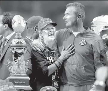  ?? Rick Scuteri Associated Press ?? URBAN MEYER and his wife hug after Ohio State’s national title game win in 2014. Meyer said he didn’t know she talked to Zach Smith’s former wife about abuse claims, but Ohio State’s report concluded otherwise.