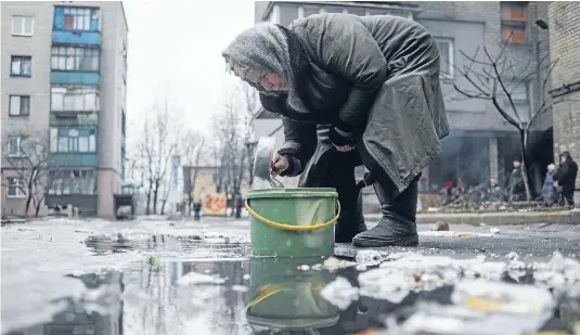  ?? Photo: REUTERS ?? Front line: An elderly woman collects water from a puddle in the Ukrainian town of Debaltseve, under attack by pro-Russian separatist­s.