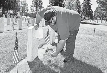  ?? MATTHEW BROWN/AP ?? Frank Groblebe places flowers to honor his parents, Frank and Helen Groblebe, on Memorial Day in Billings, Montana.