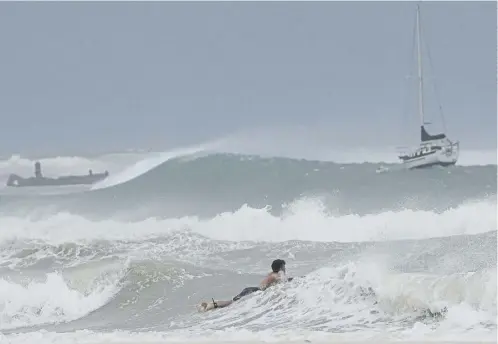  ?? ?? A surfer braves the waves in Carlisle Bay as Hurricane Beryl passes through Bridgetown, Barbados, below