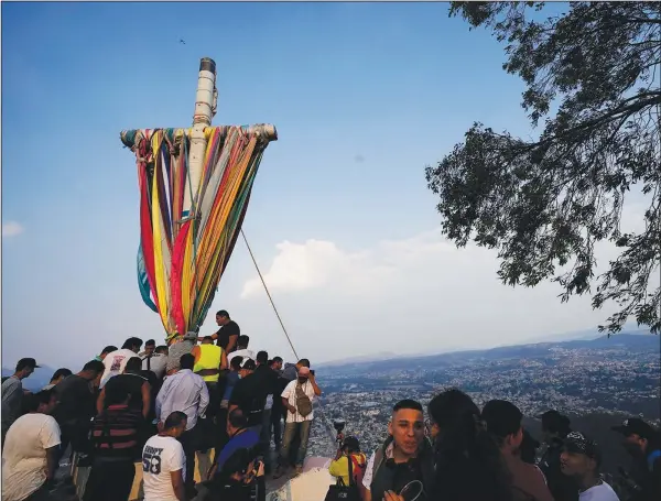  ?? (Ap/eduardo Verdugo) ?? People gather around a heavy, wooden cross Monday before lowering it from the hilltop as part of celebratio­ns marking the Day of the Cross in the Santa Cruz Xochitepec neighborho­od of Mexico City.