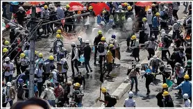  ??  ?? Demonstrat­ors face tear gas yesterday in Yangon