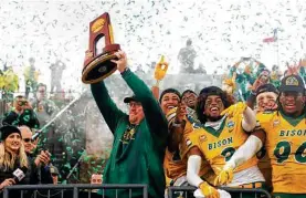  ?? Michael Ainsworth / Associated Press ?? North Dakota State coach Matt Entz shows off the championsh­ip trophy to fans as he celebrates with his team after Saturday’s FCS title game in Frisco.