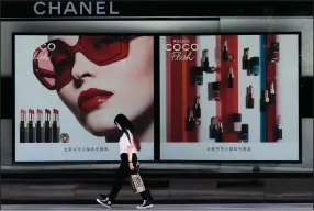  ?? (AP/Andy Wong) ?? A woman walks past an advertisem­ent for Chanel lipstick on a billboard in Beijing in May.