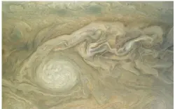  ??  ?? Een snapshot van het wolkendek op Jupiter. De grote witte ovale plek is een gigantisch­e storm (cycloon) die tegen de klok in draait.