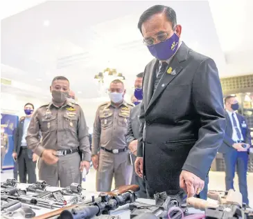  ?? ROYAL THAI GOVERNMENT HOUSE ?? Prime Minister Prayut Chan-o-cha looks at weapons seized in a drugs crackdown during his visit to the Office of the Narcotics Control Board on Din Daeng Road in the capital yesterday.