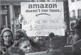  ?? AP PHOTOS/BEBETO MATTHEWS ?? Protesters hold up anti-Amazon signs on Nov. 14 during a rally and press conference of elected officials, community organizati­ons and unions opposing Amazon headquarte­rs getting subsidies to locate in Long Island City, in New York.