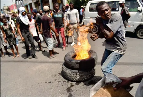  ??  ?? A demonstrat­or avoids getting burned after he set fire to tires during a march through the streets of Port-auPrince, on Saturday to protest against the government of President Jovenel Moise and against Prime Minister Jack Guy Lafontant, who later presented his resignatio­n.