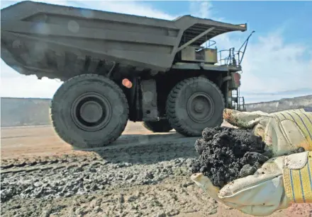  ??  ?? A mine worker holds a handful of tar sands oil at a mine located 35 miles north of Fort McMurray, Alberta, in 2006. It takes about two tons of the material to produce one barrel of oil.