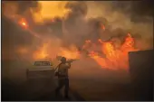  ??  ?? Firefighte­r Raymond Vasquez braves tall flames as he fights the advancing Silverado Fire, fueled by Santa Ana winds, in Irvine on Monday.