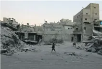  ?? Abdalrhman Ismail / Reuters ?? A boy walks past damaged buildings in the rebel-held Al Kalaseh neighbourh­ood in Aleppo.