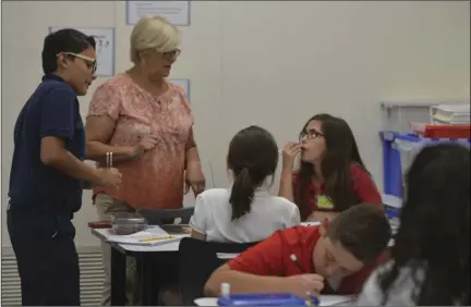  ?? EDWIN DELGADO PHOTO ?? Sixth-grade teacher Helen Wong helps her students with an experiment with tune forks which explores the relationsh­ip between sound and vibrations.