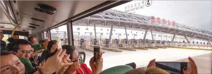  ?? ROY LIU / CHINA DAILY ?? Passengers take photos on board a shuttle bus on the Hong Kong-Zhuhai-Macao Bridge on Wednesday.