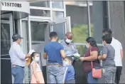  ?? JULIO CORTEZ — THE ASSOCIATED PRESS ?? A security officer meets with people outside the federal building to give them a form to return for immigratio­n check-ins at a later date on Monday in Baltimore.