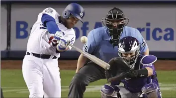  ??  ?? Los Angeles Dodgers’ Max Muncy (left) hits a solo home run as Colorado Rockies catcher Tony Wolters (right) watches along with home plate umpire Ryan Blakney during the fourth inning of a baseball game on Monday, in Los Angeles. AP PHOTO/MARK J. TERRILL