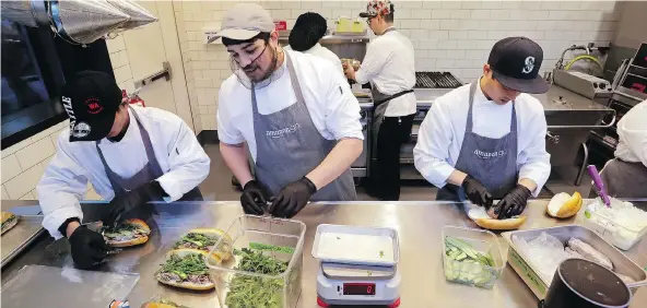  ?? ELAINE THOMPSON / THE ASSOCIATED PRESS FILES ?? Workers make sandwiches in an Amazon Go store in Seattle. The company is boosting its minimum wage for all U.S. workers to $15 per hour starting next month, a move that will benefit more than 350,000 workers.