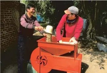  ?? — Julie Roberson ?? Timothy Heinze ( right) sifts through coffee beans with Hu Xixiang, the owner of a farm in Yunnan Province, whose coffee has been sold nationwide and around the world.