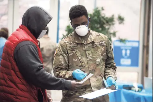  ?? Ned Gerard / Hearst Connecticu­t Media ?? A member of the Connecticu­t National Guard checks a man in for a COVID-19 test at the new testing site on the University of Connecticu­t Stamford campus on Thursday.