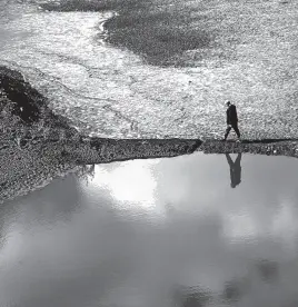  ?? REUTERS ?? A man walks by the Canelon Grande reservoir in Canelones, Uruguay, on May 18, amid a historic drought that has left reservoirs dry and Montevideo with only days worth of water, sparking protests and forcing the government to subsidize bottled water.