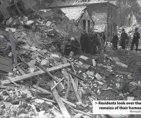  ?? Mirrorpix ?? > Residents look over the remains of their homes