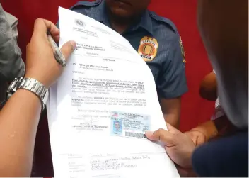  ?? SUNSTAR FOTO / ALAN TANGCAWAN ?? SERVED. Antonio Rosellosa, whose identifica­tion card is being verified, claims he is the security guard of Peter Lim’s house in Barangay Kasambagan, Cebu City, where the CIDG 7 served the subpoena for Lim.